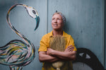 founder Kate holding a wood and natural bristle broom leaning against a door with a graffiti bird by Steve McCracken
