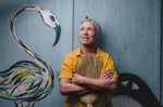 founder Kate holding a wood and natural bristle broom leaning against a door with a graffiti bird by Steve McCracken