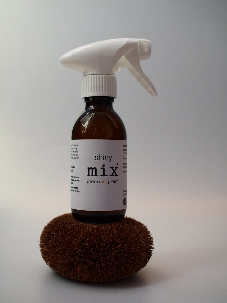 shiny mix amber glass bottle with white plastic recyclable trigger sits on a plastic free ecococnut scrub brush